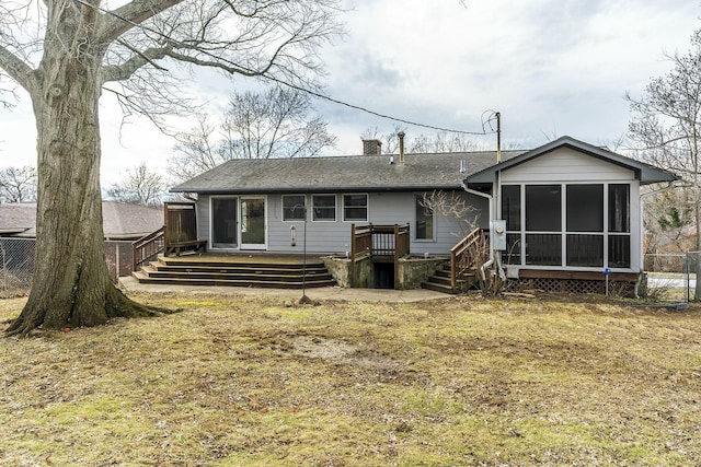 back of property with roof with shingles, a deck, a chimney, and a sunroom
