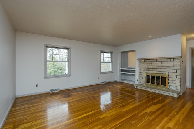 unfurnished living room featuring wood finished floors, visible vents, and a textured ceiling
