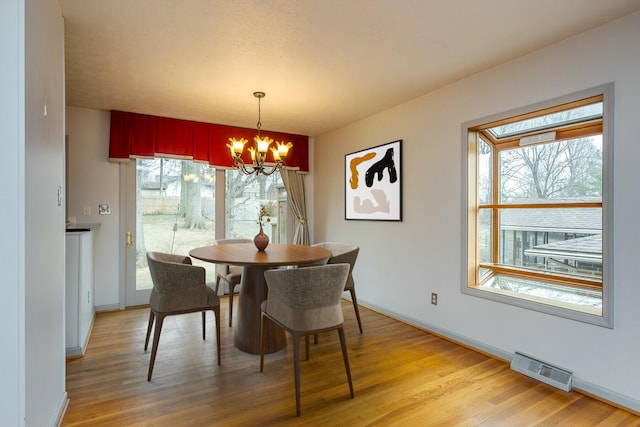 dining space featuring a notable chandelier, visible vents, baseboards, and light wood-style floors