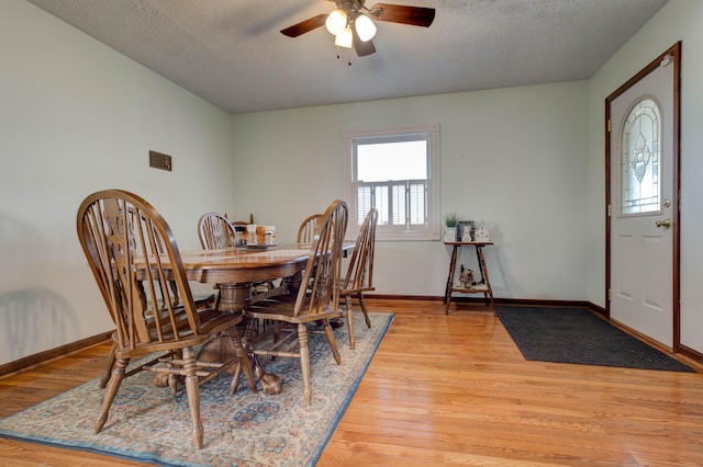 dining area featuring a ceiling fan, light wood-type flooring, a textured ceiling, and baseboards