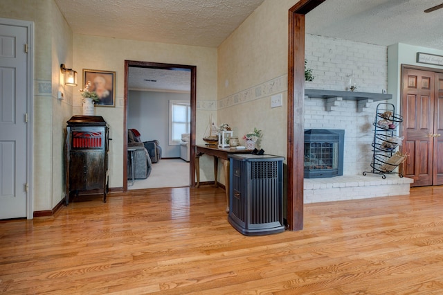 corridor featuring a textured ceiling, light wood finished floors, and baseboards