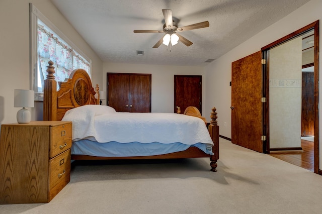 carpeted bedroom featuring ceiling fan, visible vents, and a textured ceiling