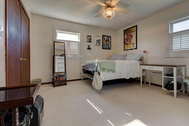 bedroom featuring a ceiling fan, light carpet, a textured ceiling, and baseboards