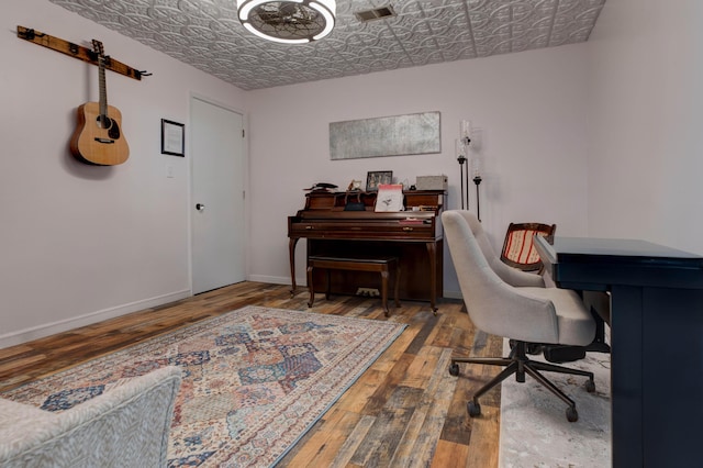 office space featuring visible vents, wood-type flooring, an ornate ceiling, and baseboards