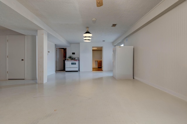 empty room featuring light floors, baseboards, visible vents, and a textured ceiling