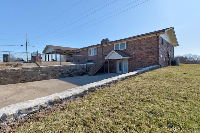 view of front of house with brick siding, stairway, central AC unit, fence, and a front lawn