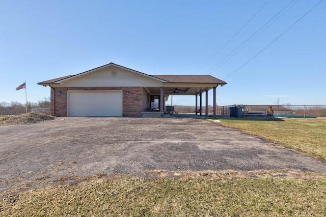 view of front of home with covered porch, a garage, brick siding, a carport, and a front yard