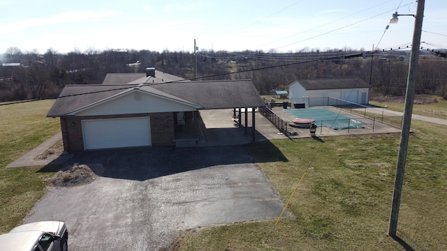 exterior space featuring a garage, brick siding, a front yard, and a fenced in pool