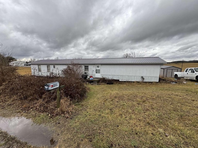 view of front facade with a front yard, metal roof, and an outbuilding