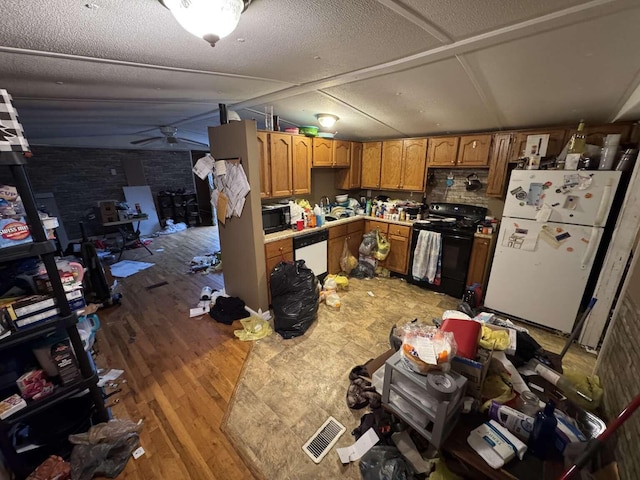 kitchen featuring lofted ceiling, wood finished floors, light countertops, a textured ceiling, and black appliances