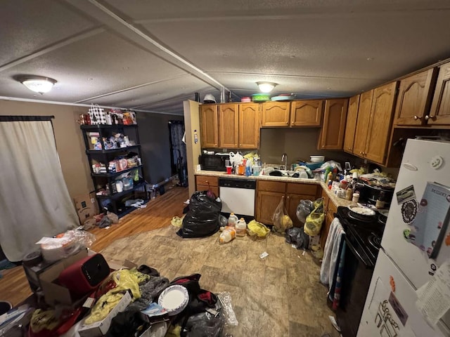 kitchen featuring a sink, light countertops, freestanding refrigerator, brown cabinets, and dishwasher