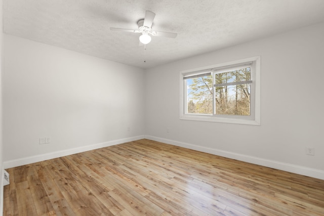 empty room with light wood-type flooring, ceiling fan, a textured ceiling, and baseboards