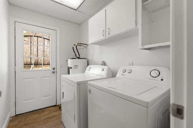 washroom with dark wood-type flooring, washer and dryer, electric water heater, and cabinet space