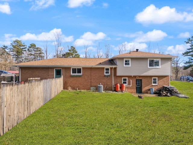 rear view of property with fence, a lawn, and brick siding