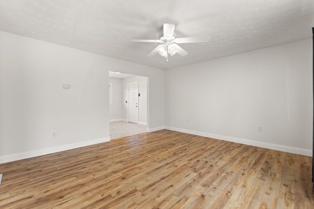 spare room featuring ceiling fan, light wood finished floors, and baseboards