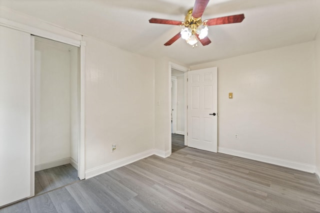 interior space with light wood-type flooring, a closet, ceiling fan, and baseboards