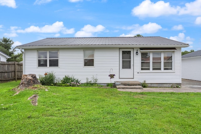 view of front of house featuring metal roof, a front lawn, and fence