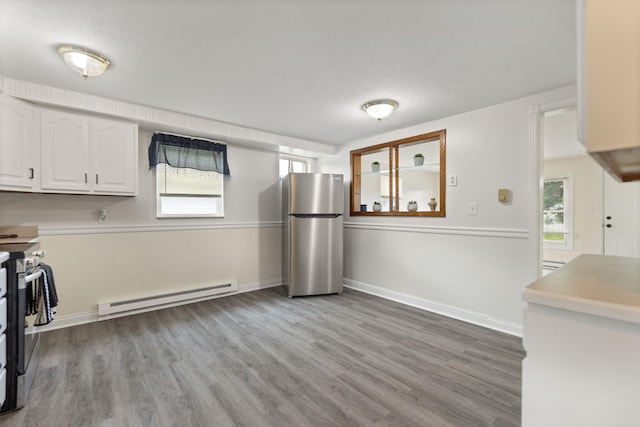 kitchen with stainless steel appliances, light wood finished floors, a baseboard radiator, and white cabinetry