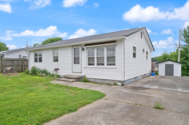 view of front of house with an outbuilding, metal roof, a storage shed, fence, and a front yard