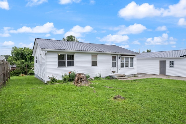 rear view of property featuring fence, metal roof, and a yard