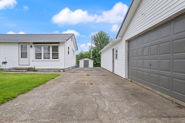 view of side of property with a garage, an outbuilding, metal roof, and a lawn