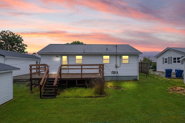 back of house at dusk featuring metal roof, stairs, a deck, and a lawn