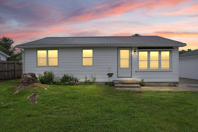 back of house with fence, metal roof, and a yard