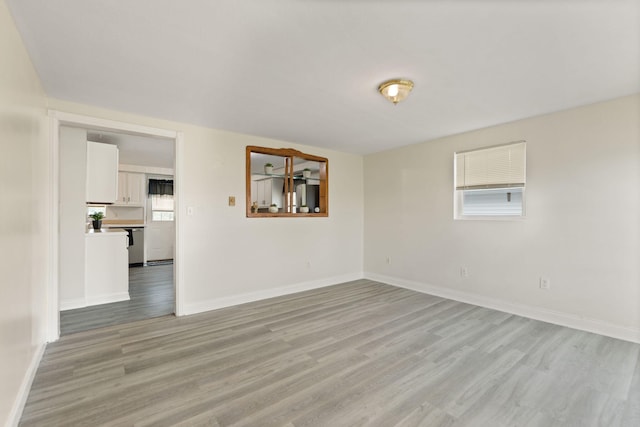 unfurnished room with light wood-type flooring and baseboards