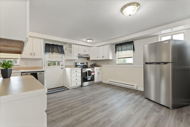 kitchen with appliances with stainless steel finishes, a baseboard radiator, white cabinetry, and under cabinet range hood