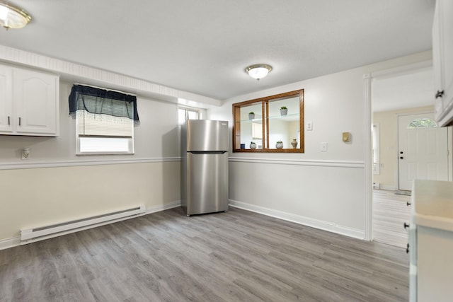 kitchen with light wood finished floors, baseboard heating, freestanding refrigerator, and white cabinets