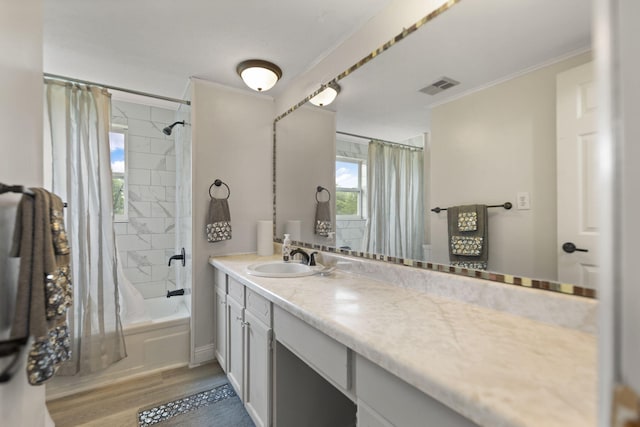 full bath with shower / tub combo, visible vents, ornamental molding, wood finished floors, and vanity