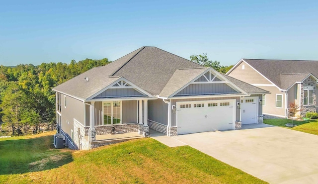 craftsman-style home with a shingled roof, concrete driveway, an attached garage, a porch, and a front yard