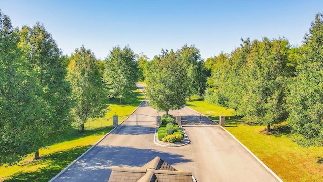 exterior space with a gate, fence, and a lawn