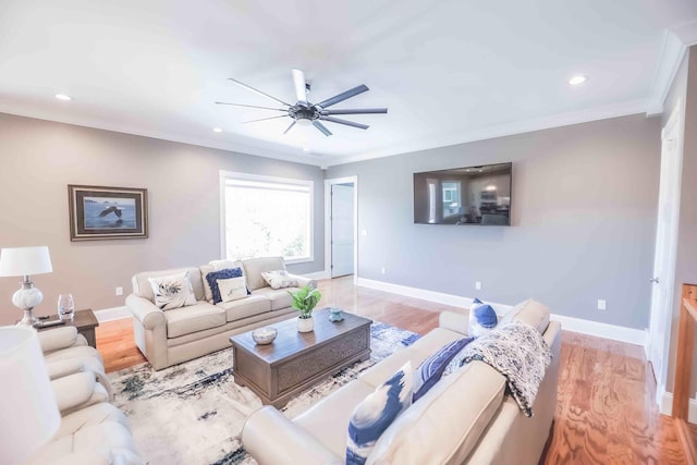 living area with ornamental molding, light wood-style floors, a ceiling fan, and baseboards