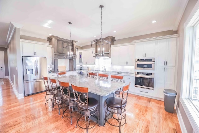 kitchen with a spacious island, appliances with stainless steel finishes, white cabinets, and decorative light fixtures