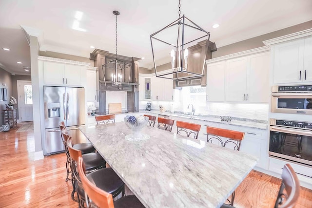 kitchen featuring hanging light fixtures, appliances with stainless steel finishes, a spacious island, and a breakfast bar area