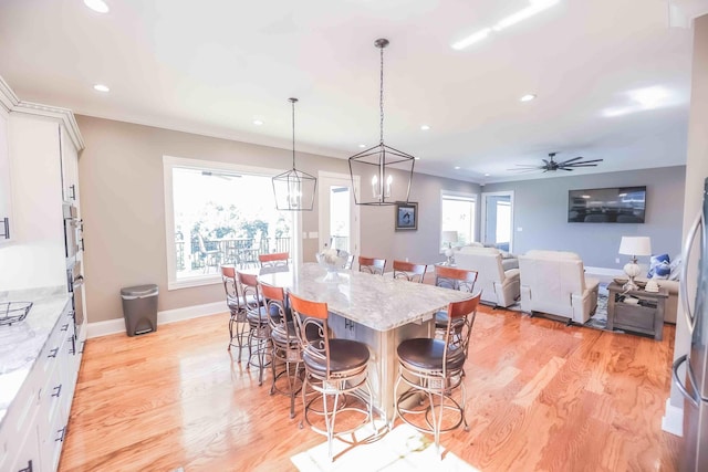 kitchen with a breakfast bar, a kitchen island, pendant lighting, and white cabinets