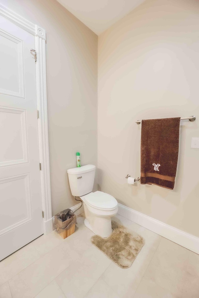 half bath with tile patterned flooring, toilet, and baseboards