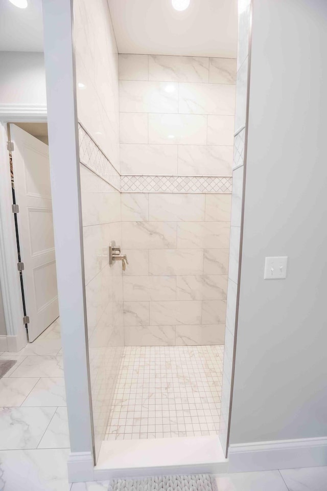 bathroom featuring marble finish floor, baseboards, and a walk in shower