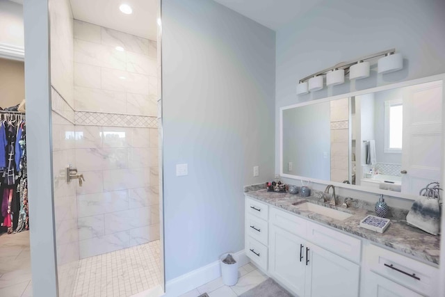 full bathroom featuring vanity, a spacious closet, baseboards, and walk in shower