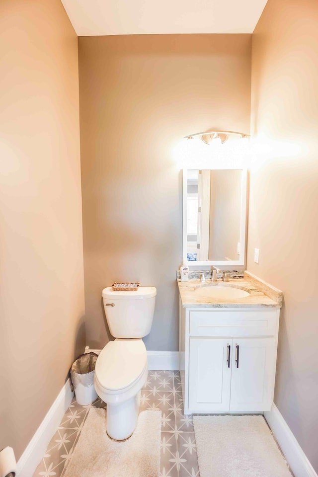 half bathroom featuring tile patterned floors, vanity, toilet, and baseboards