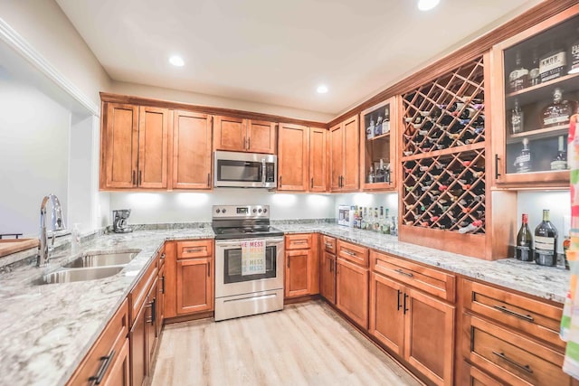 kitchen with light stone countertops, glass insert cabinets, stainless steel appliances, and a sink