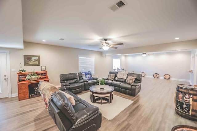 living room with light wood-style floors, visible vents, and baseboards