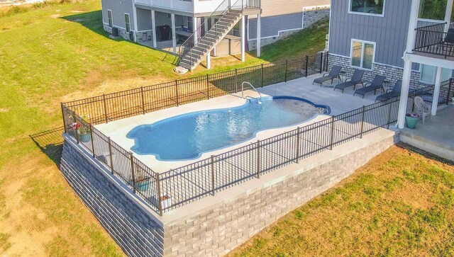 view of pool featuring a patio, fence, stairs, a yard, and a fenced in pool