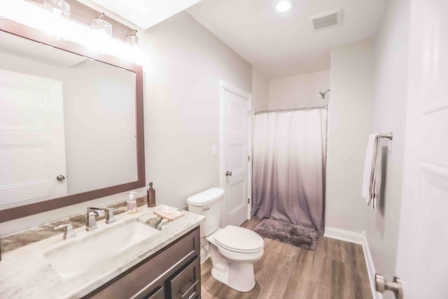 full bath featuring toilet, wood finished floors, vanity, visible vents, and baseboards