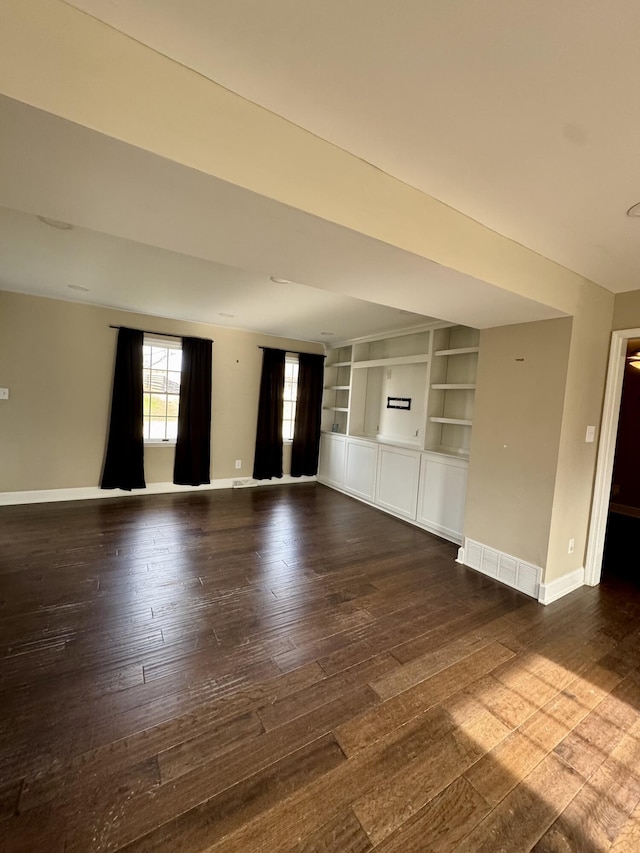 spare room featuring dark wood-style flooring, built in features, and baseboards