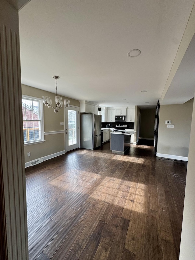 kitchen with decorative light fixtures, light countertops, appliances with stainless steel finishes, white cabinets, and a kitchen island