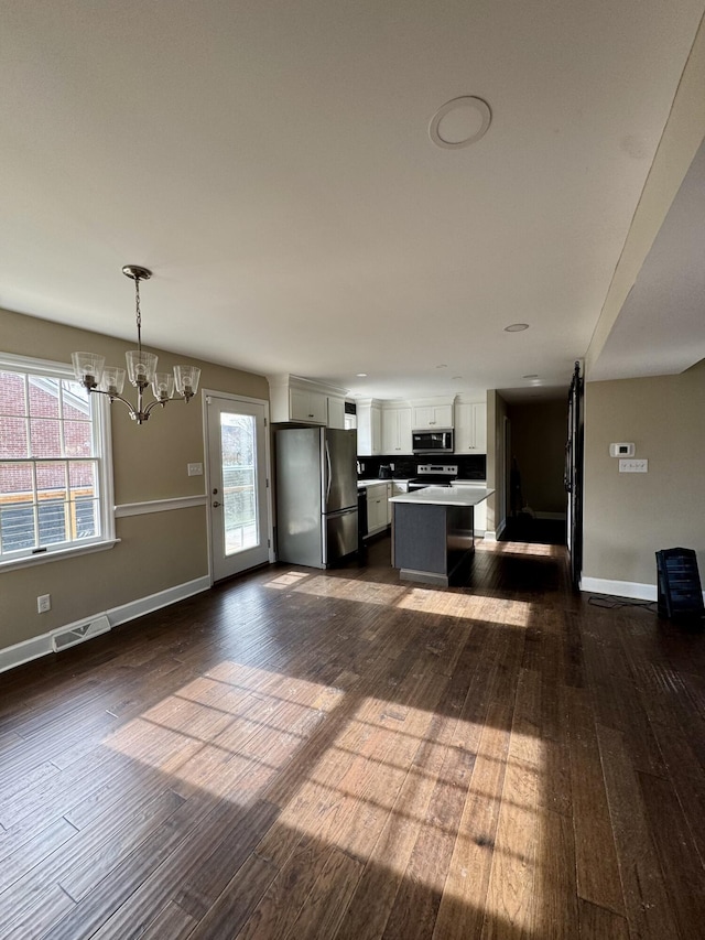 kitchen with visible vents, appliances with stainless steel finishes, decorative light fixtures, a center island, and light countertops