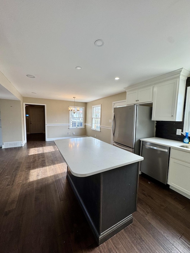 kitchen with stainless steel appliances, a kitchen island, and light countertops