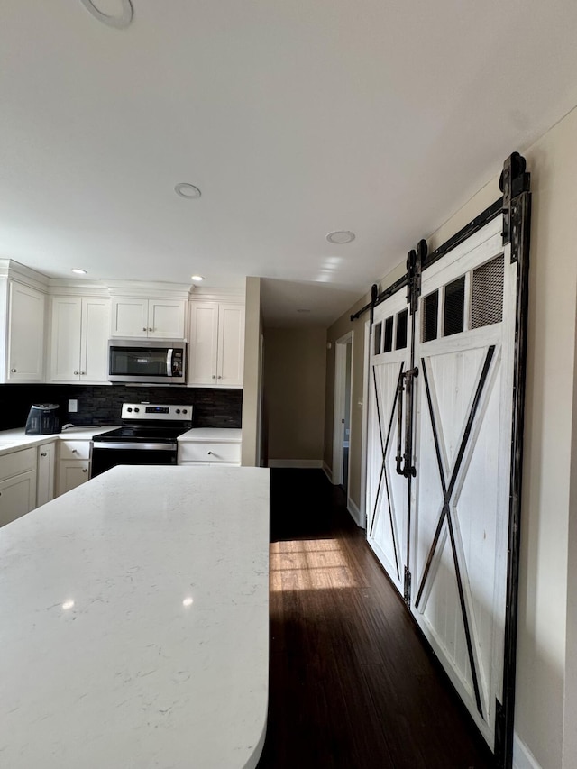 kitchen featuring dark wood finished floors, tasteful backsplash, stainless steel microwave, white cabinets, and range with electric cooktop